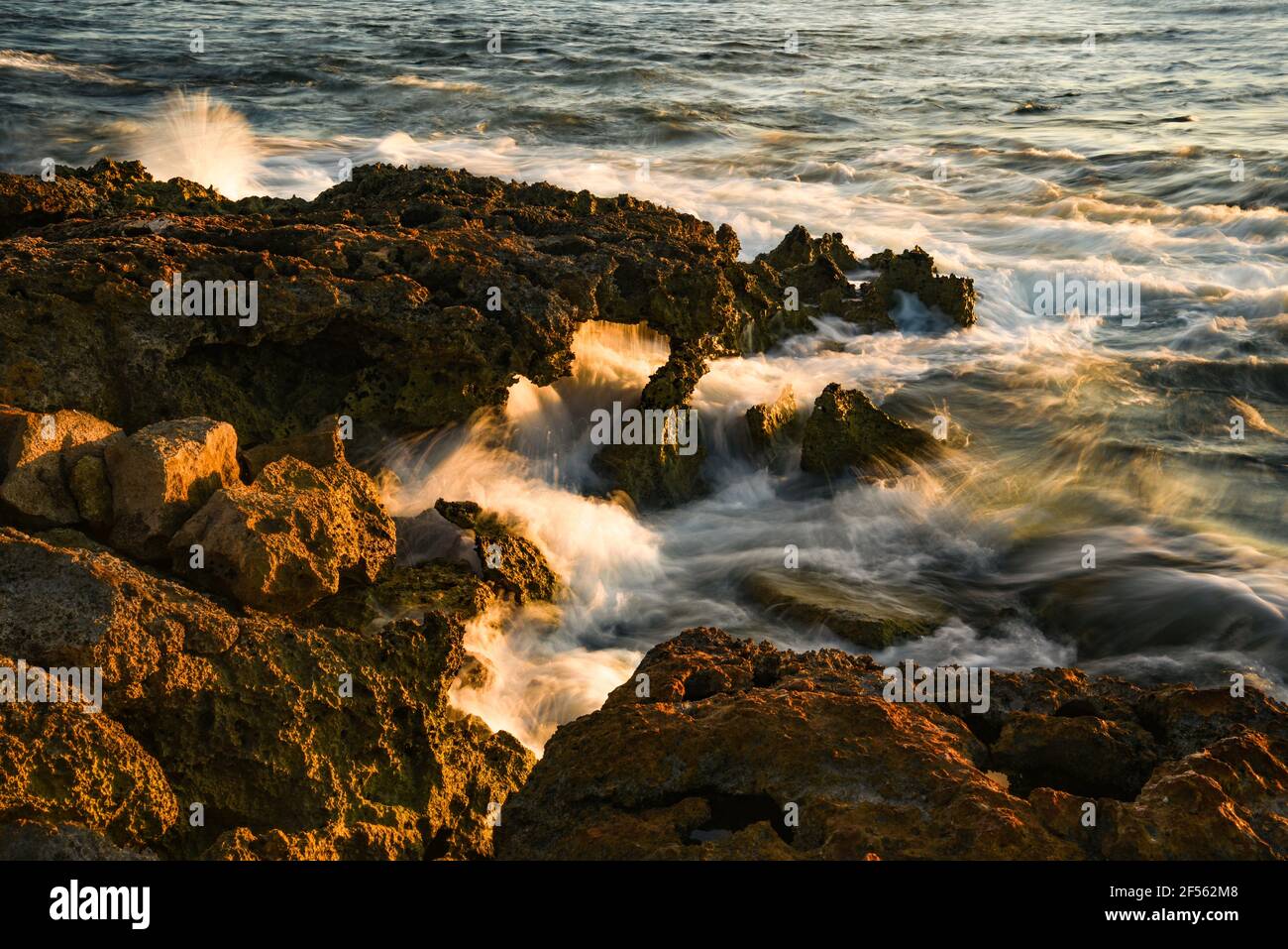 Sfocatura del movimento dell'acqua, acqua sulle rocce a Paradise Cove, onde dell'oceano Pacifico che si infrangono su rocce vulcaniche lungo la costa idilliaca, Kapolei, Oahu, Hawaii, USA Foto Stock