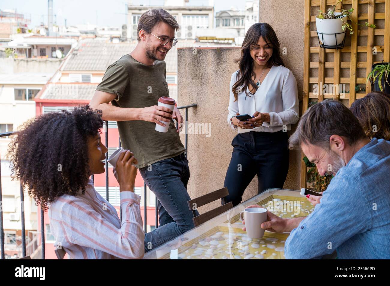 Sorridendo i colleghi di sesso maschile e femminile in balcone durante la pausa caffè in ufficio Foto Stock