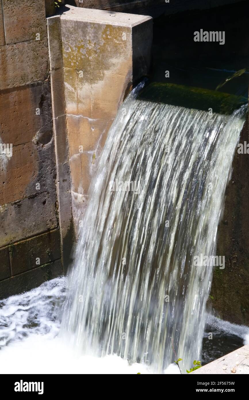 Vista verticale dell'acqua che scorre attraverso un canale sul canale che crea un impasto schiumoso alla base del cade Foto Stock