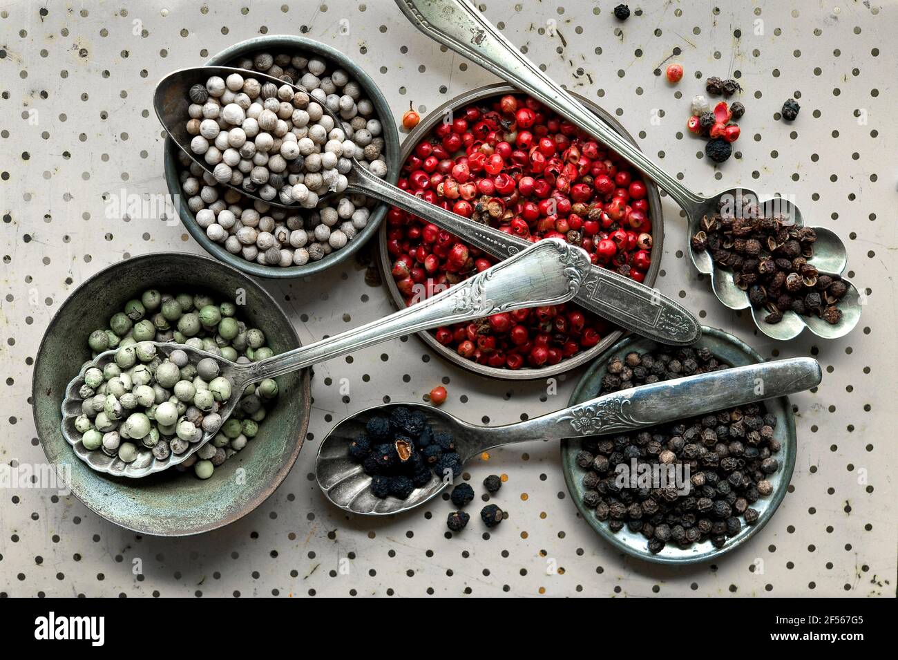 Diversi tipi di pepe in cucchiai, pepe bianco, pepe rosso, pepe di Szechuan, pepe verde, pepe nero Foto Stock