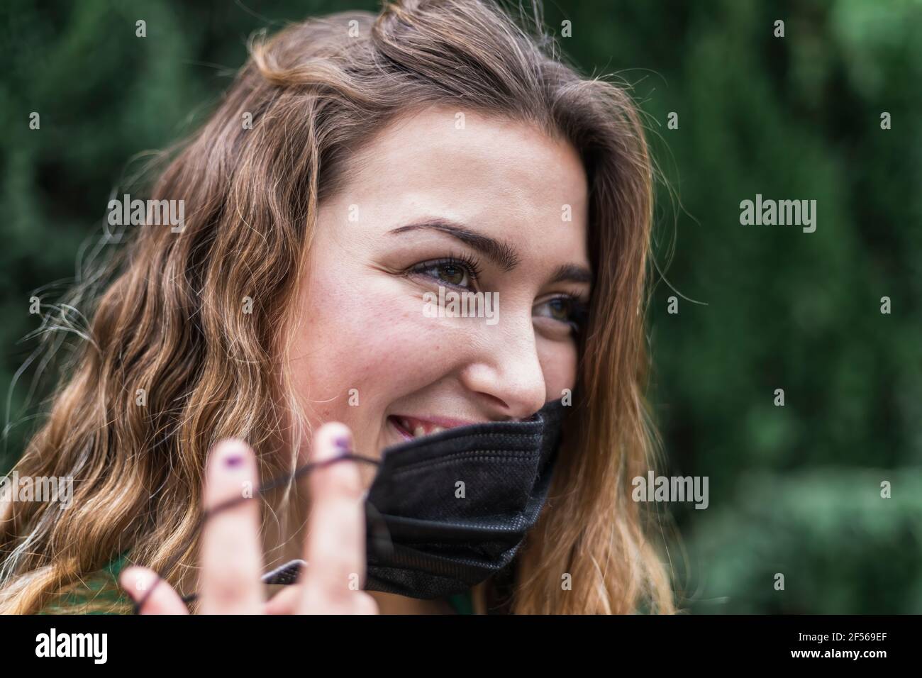 Giovane donna che prende la maschera protettiva del viso Foto Stock