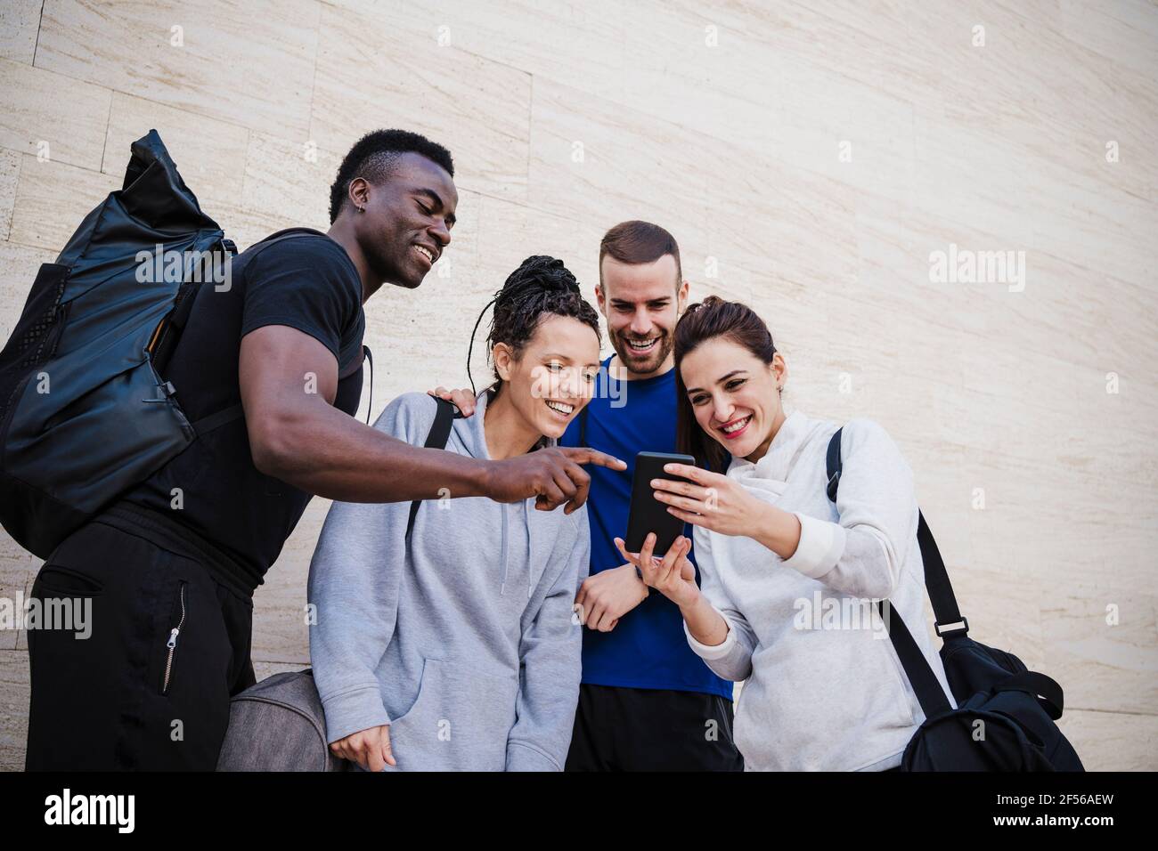 Sorridendo uomini e donne di sport persone utilizzando smartphone da parete Foto Stock