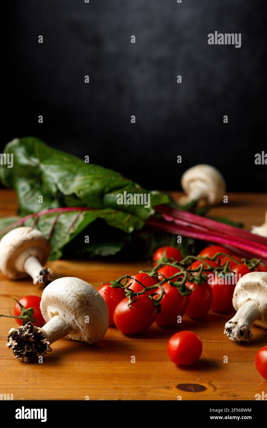 Pomodori ciliegini rossi con funghi commestibili e garzetta su tavola di legno Foto Stock