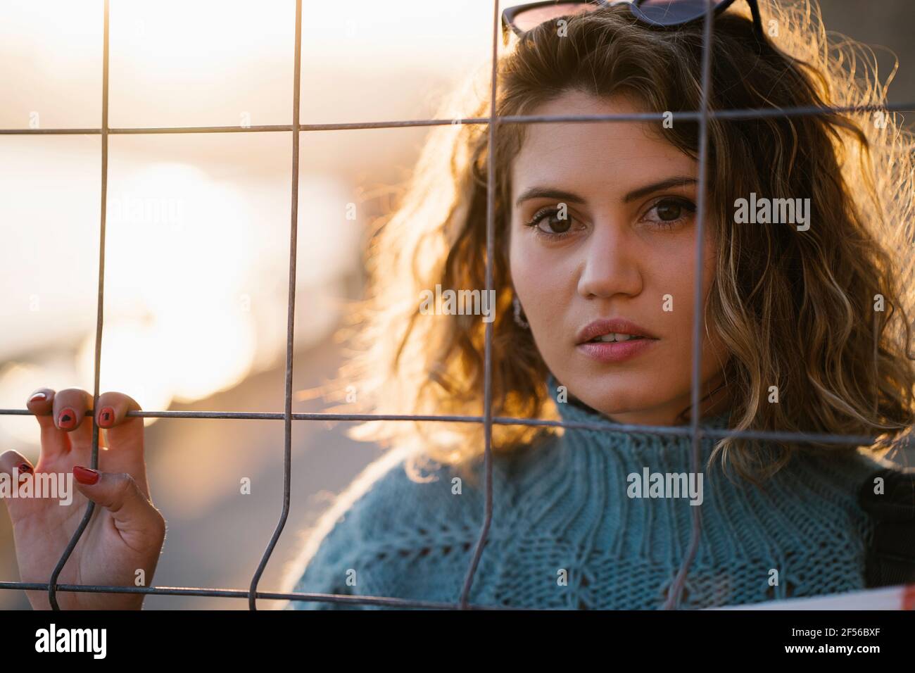 Bella donna che guarda attraverso recinzione durante la primavera sera Foto Stock