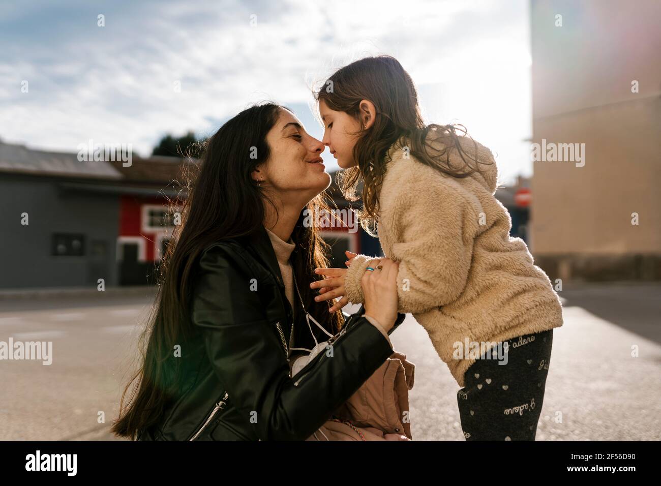 Figlia sfregando il naso con la madre mentre si sta in piedi sulla strada Foto Stock