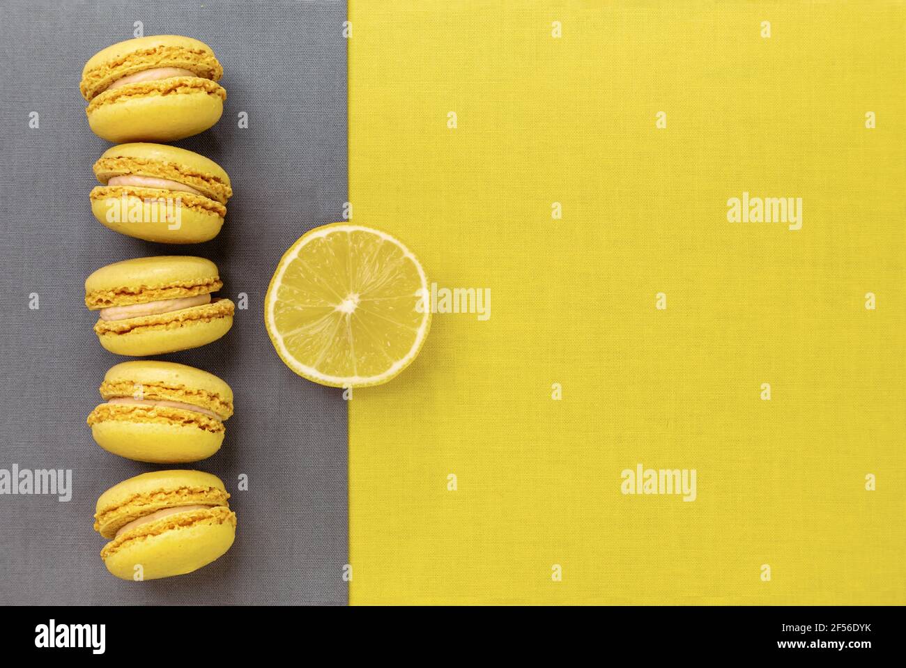 Colore trendy dell'anno 2021. Giallo luminoso e grigio estremo. Amaretti gialli e un limone su fondo grigio, piatto. Foto Stock