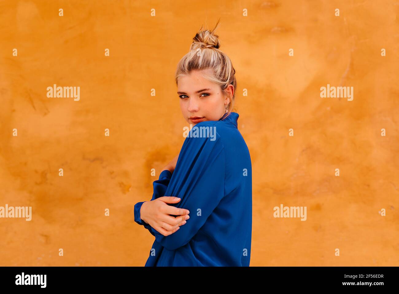 Bella donna in camicia blu scuro in piedi contro il muro giallo Foto Stock