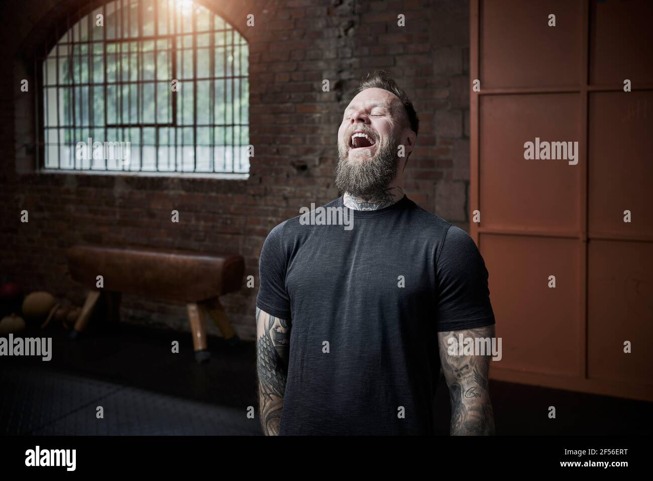 Allenatore di fitness maschile che ride mentre si trova in palestra Foto Stock