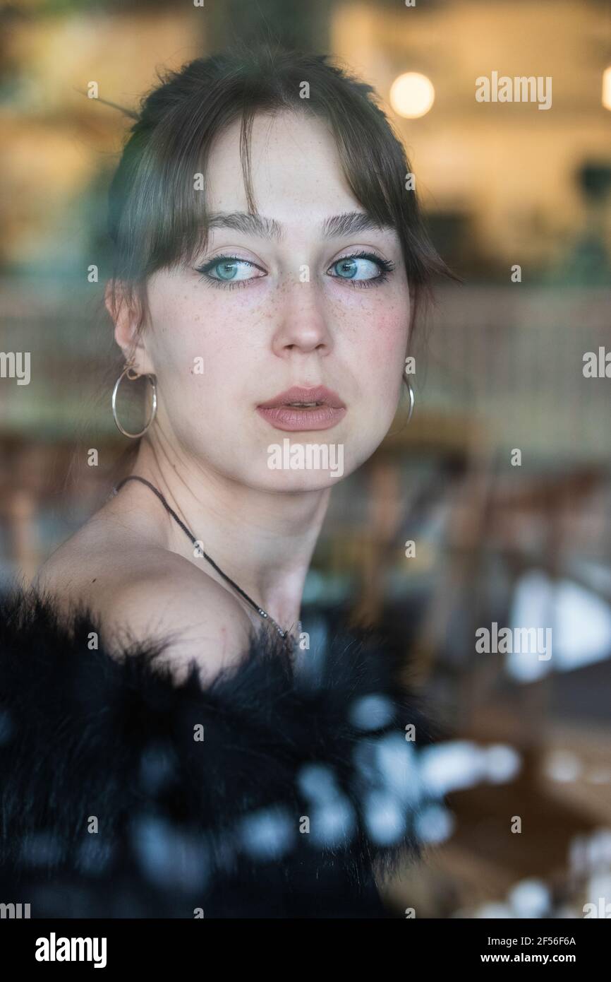 Bella donna con gli occhi blu che guardano attraverso la finestra del caffè Foto Stock