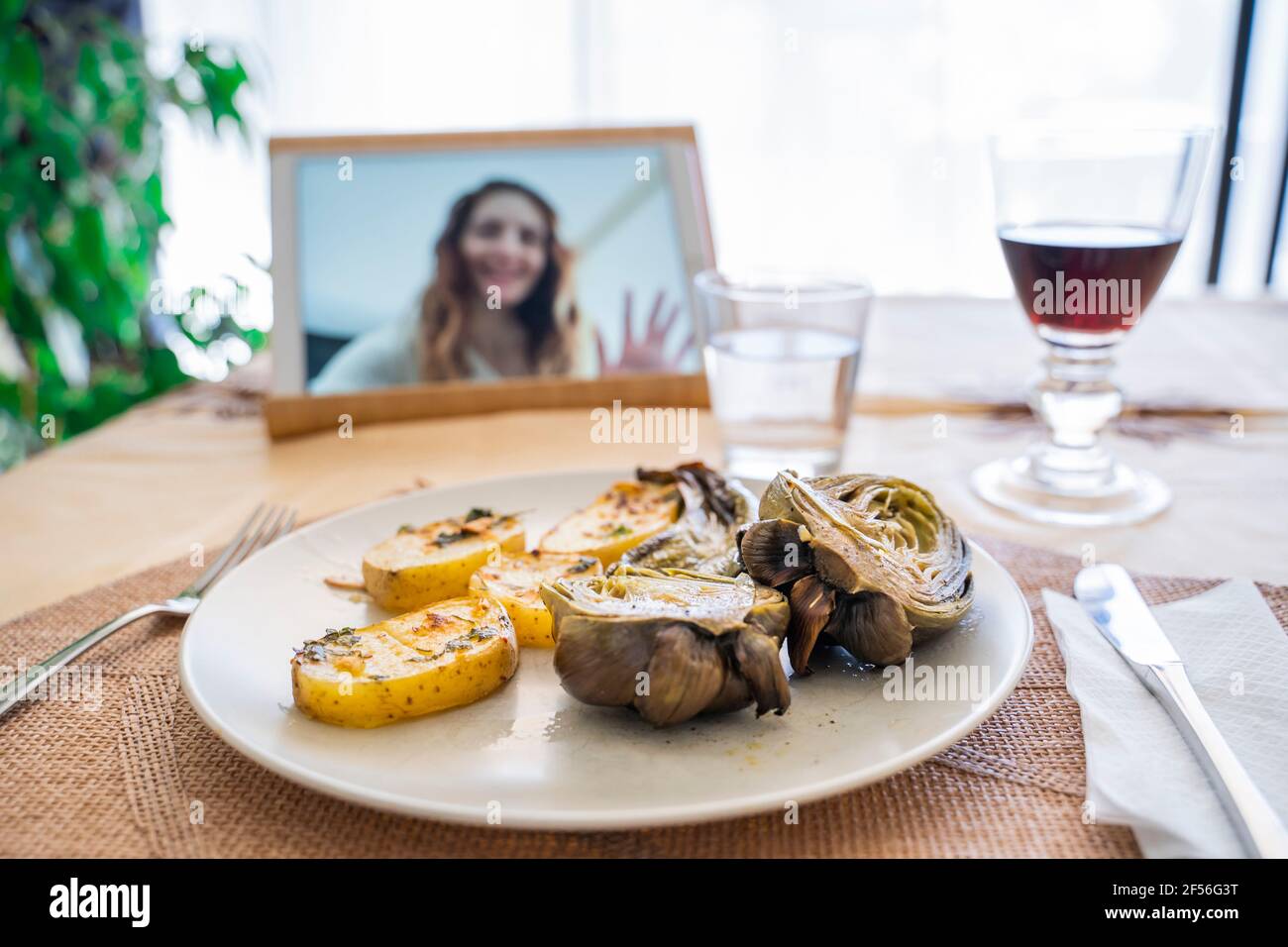 Pranzo al tavolo mentre la donna ha visto sullo schermo del digitale tablet Foto Stock