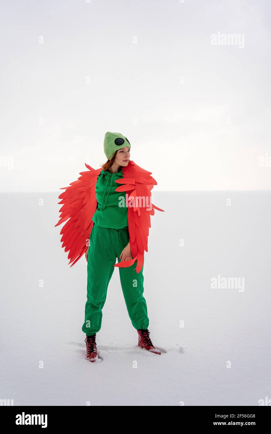 Donna in costume da uccello con le ali che si guardano in piedi contro il cielo Foto Stock
