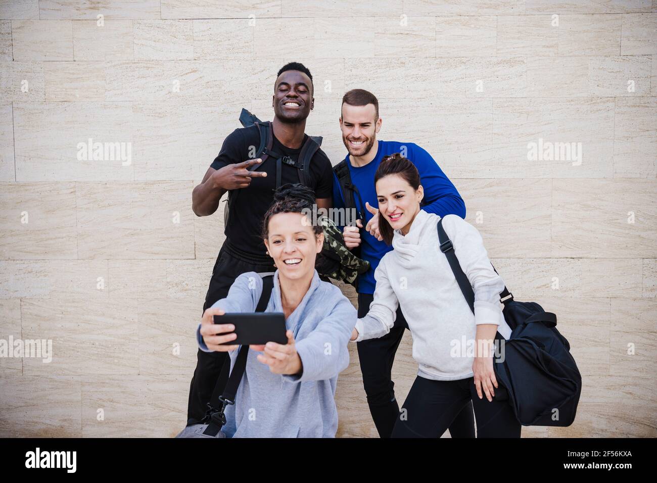 Sorridente sportivo maschile e femminile persone che prendono selfie davanti di muro Foto Stock