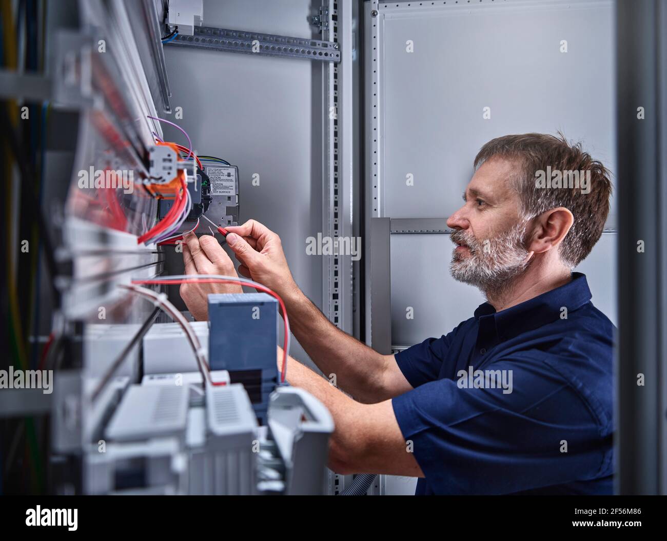 Elettricista maschio che esamina l'alimentazione in officina elettrica Foto Stock
