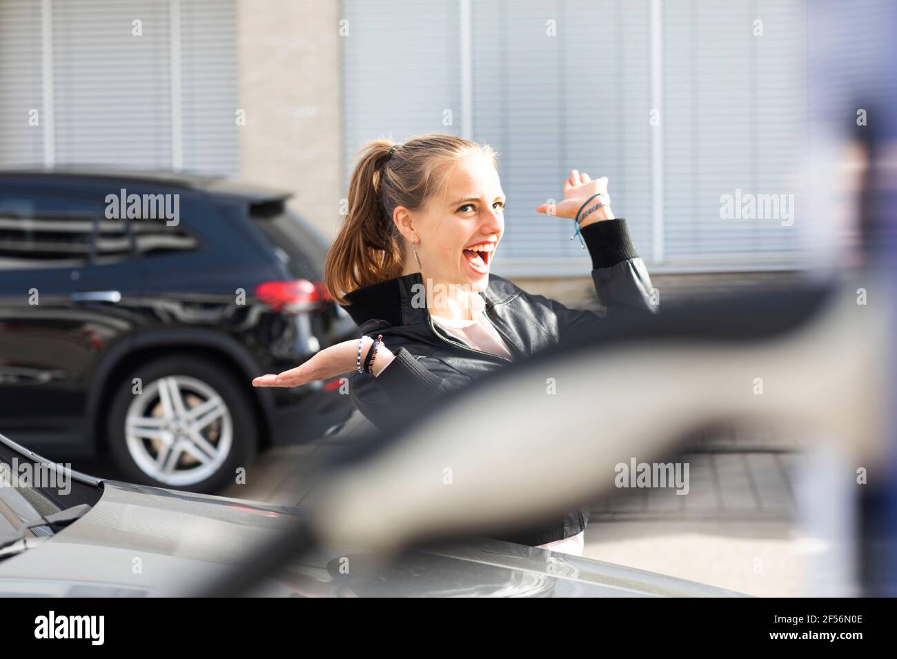 Ritratto di giovane bella bionda in piedi all'aperto e sorridente con bracci sollevati Foto Stock