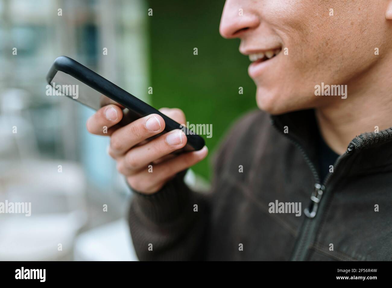 Primo piano di un uomo che invia un messaggio vocale con il suo smartphone Foto Stock