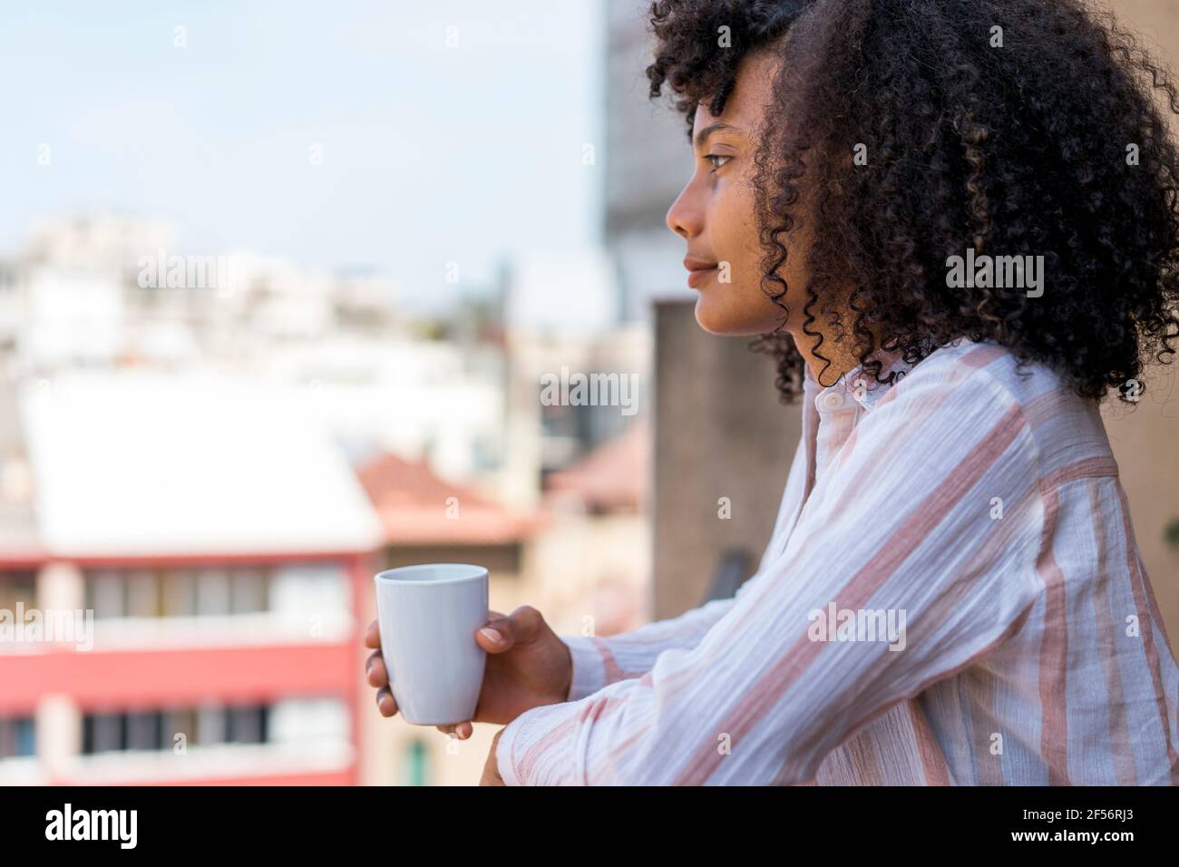 Contemplare l'imprenditore femminile in balcone durante la pausa caffè in ufficio Foto Stock