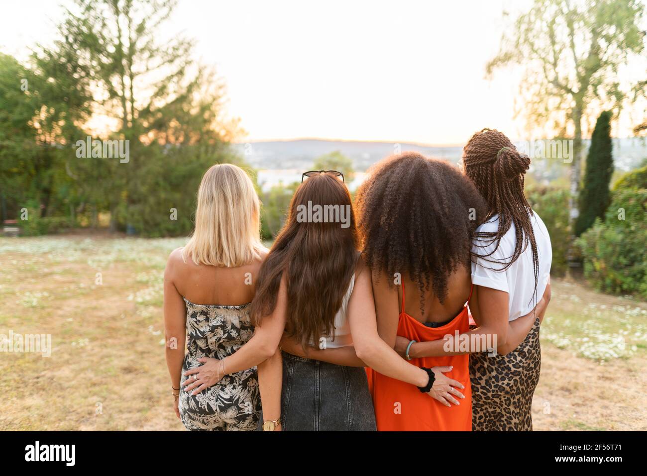 Le amiche si levano in piedi con le braccia intorno al parco Foto Stock