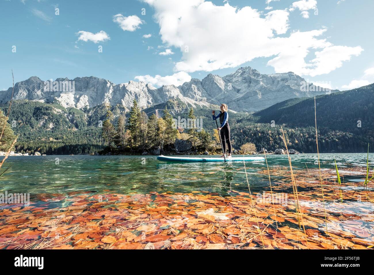 Germania, Baviera, Garmisch Partenkirchen, giovane donna levarsi in piedi sul lago Eibsee Foto Stock