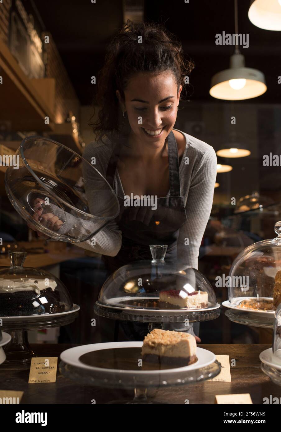 Donna felice proprietario che guarda il cibo dolce mentre lavora in panetteria Foto Stock
