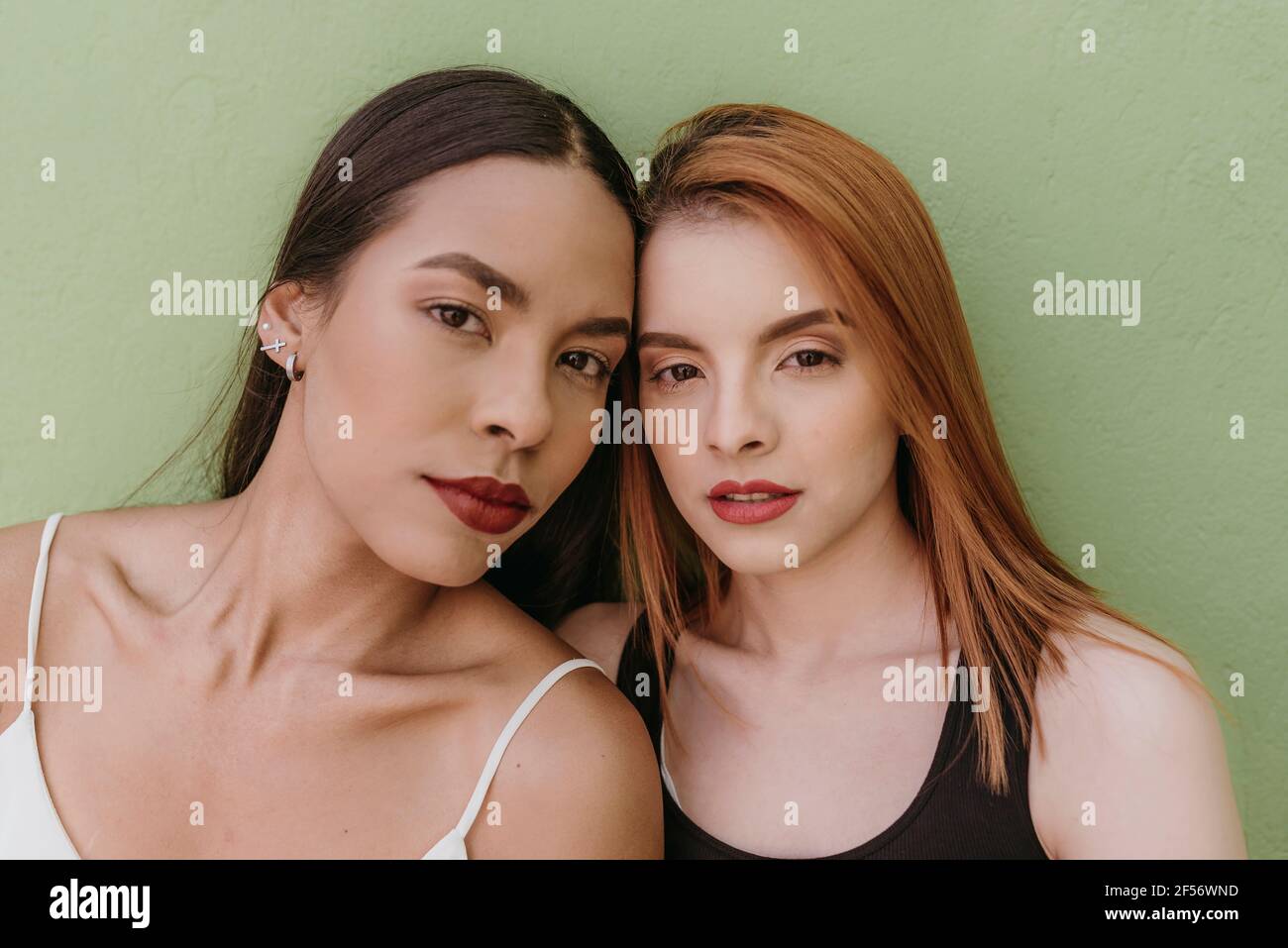 Belle donne contro parete verde Foto Stock