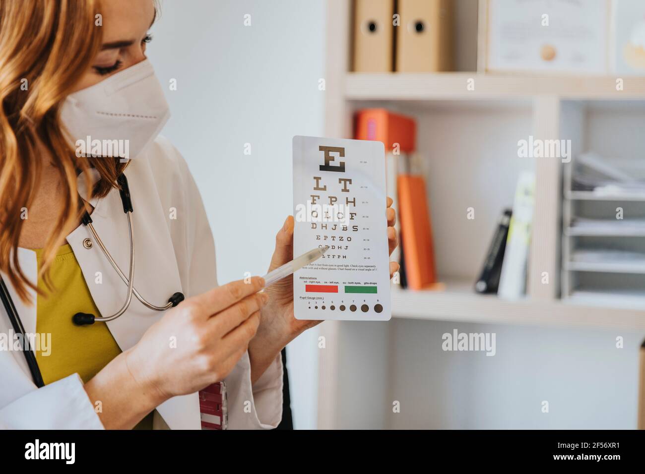 Oftalmologo femminile che punta alla mappa oculare in clinica Foto Stock