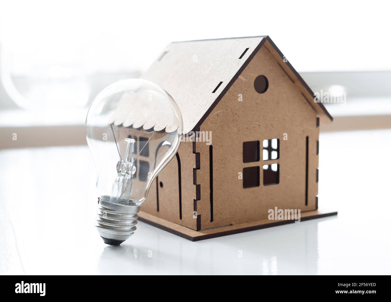 Casa modello e lampadina. Concetto di risparmio energetico. Elettricità interna. Foto Stock