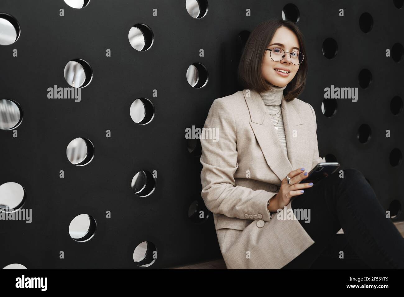 Carriera femminile, istruzione e concetto di persone. Ritratto di bella donna intelligente seduta sul pavimento e parete magra come rilassante, hanno pausa dopo corsi Foto Stock