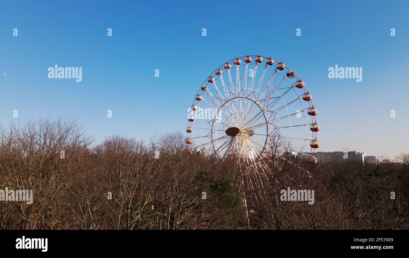 Uno scatto panoramico di un parco della città di primavera. La ruota panoramica è visibile. Foto Stock