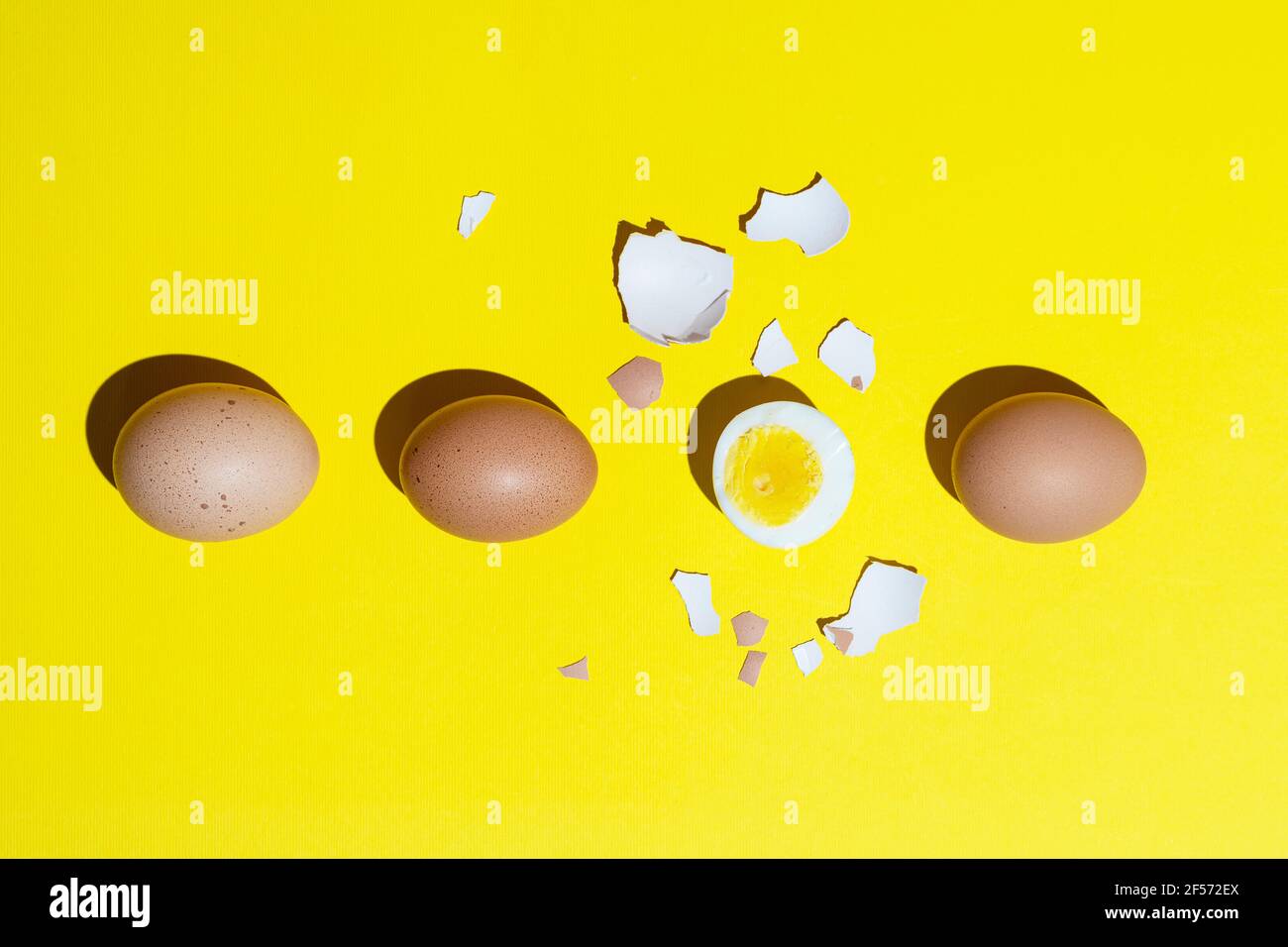 una fila di uova sode su una superficie gialla Foto Stock