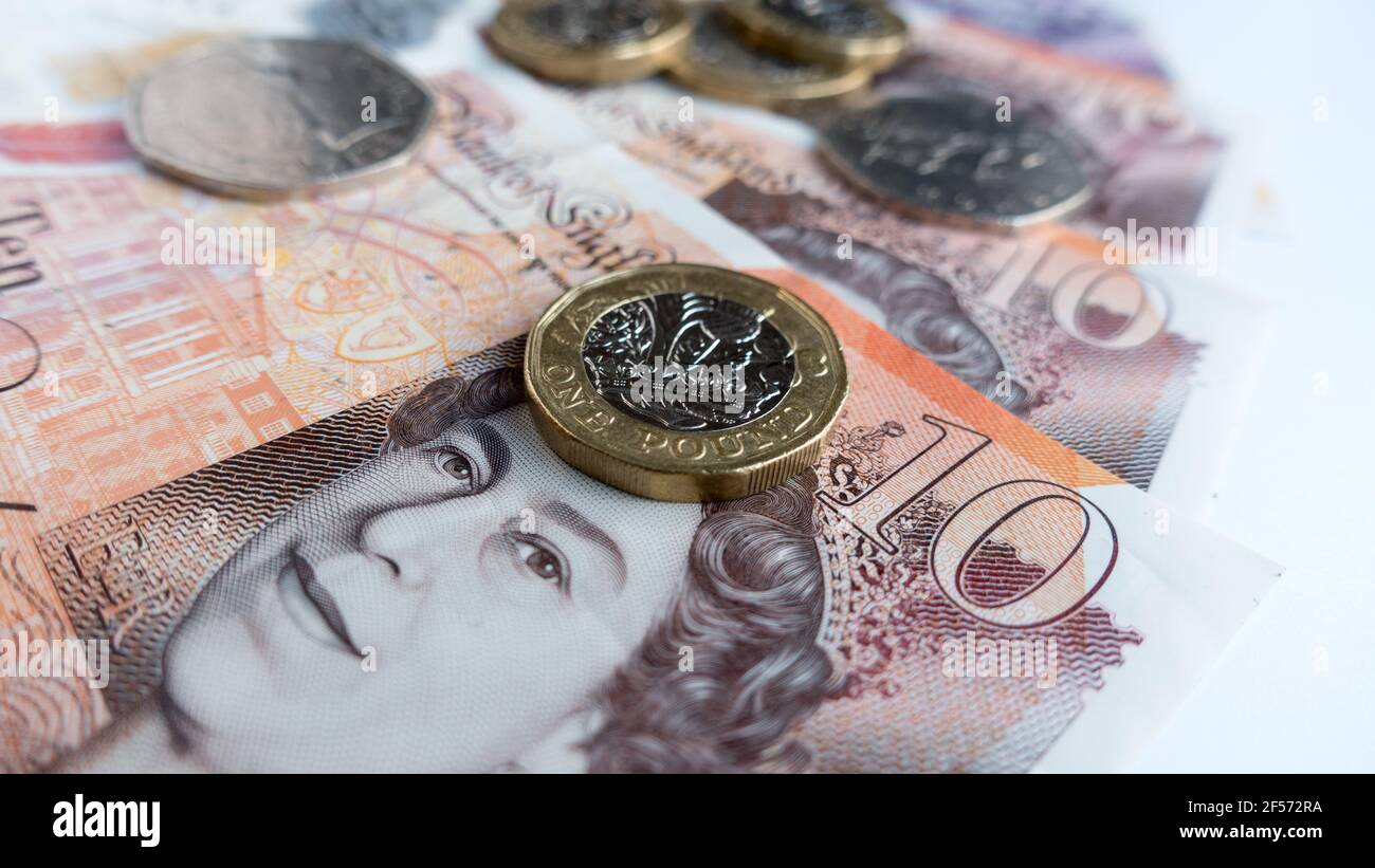 La valuta della sterlina inglese con le banconote in valuta polimerica e le monete in sterline Foto Stock