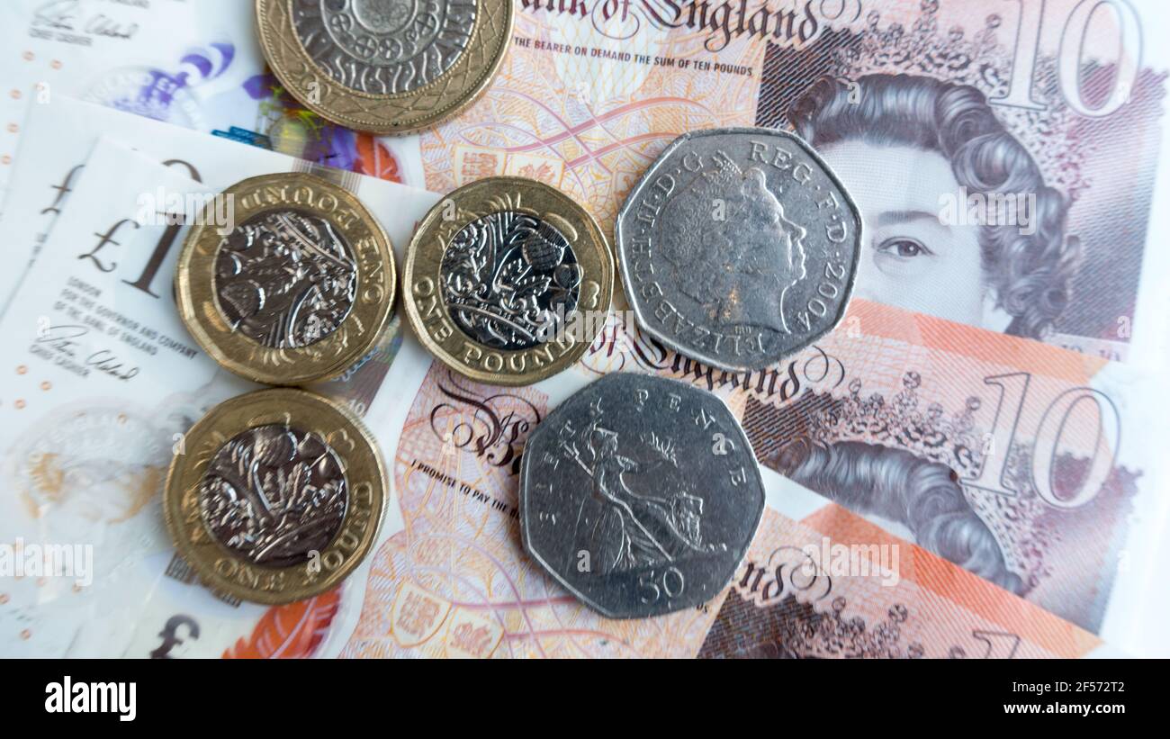La valuta della sterlina inglese con le banconote in valuta polimerica e le monete in sterline Foto Stock