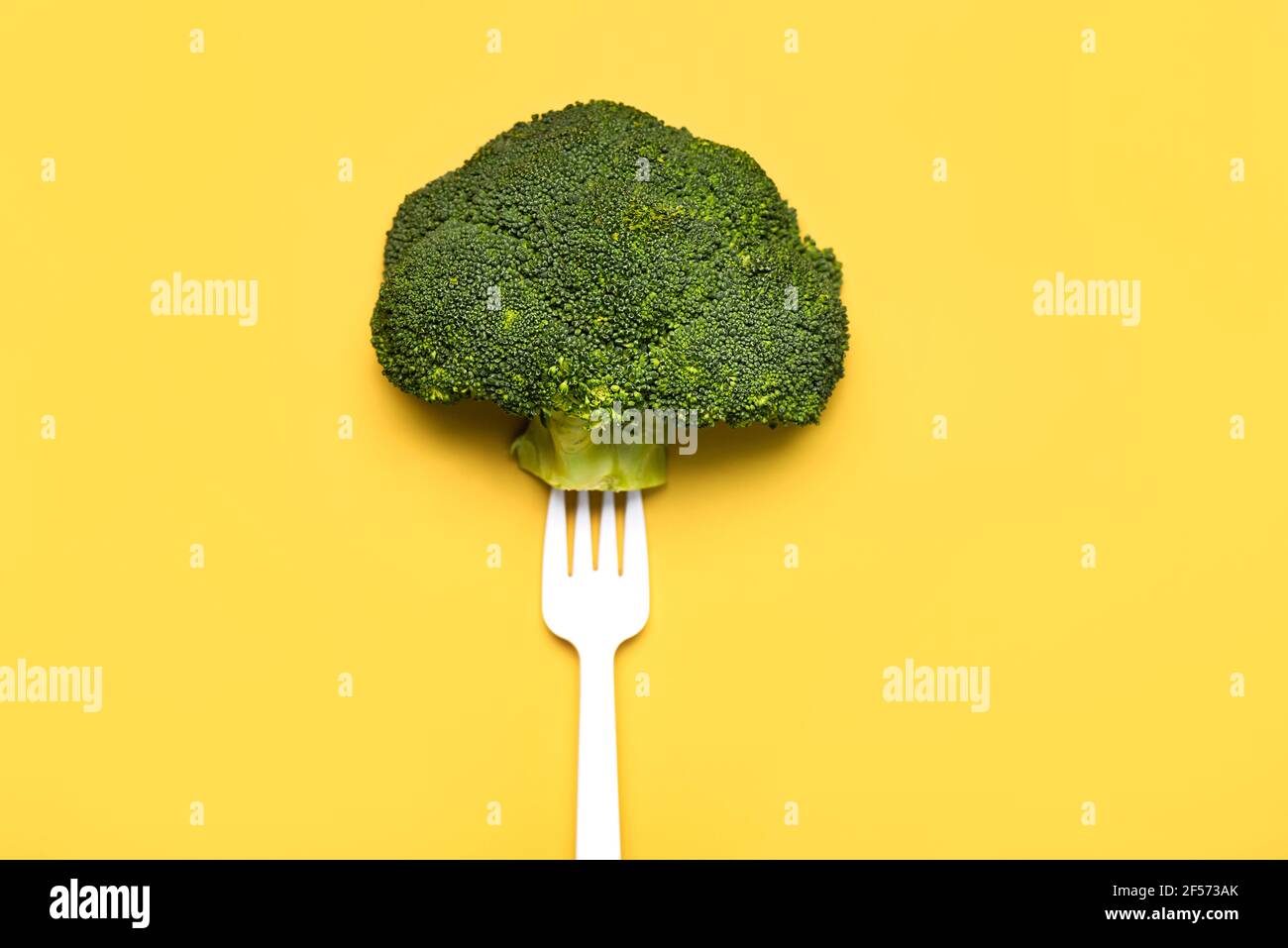 Broccoli freschi su una forchetta di plastica bianca su un giallo Background.sano stile di vita alimentare Foto Stock