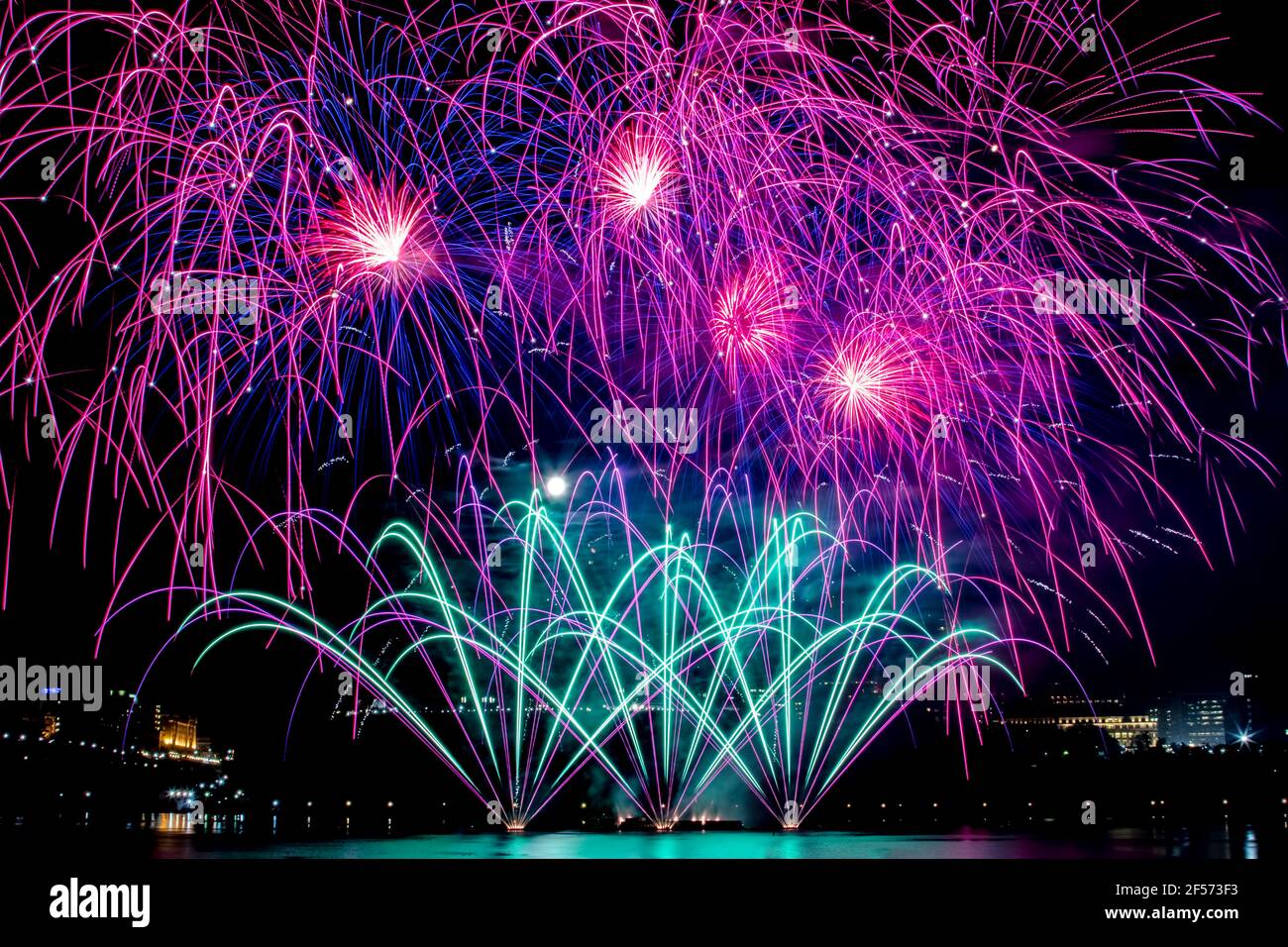 Colorati fuochi d'artificio che illuminano il cielo notturno sul Parlamento, con la luna piena che sbirra attraverso Foto Stock