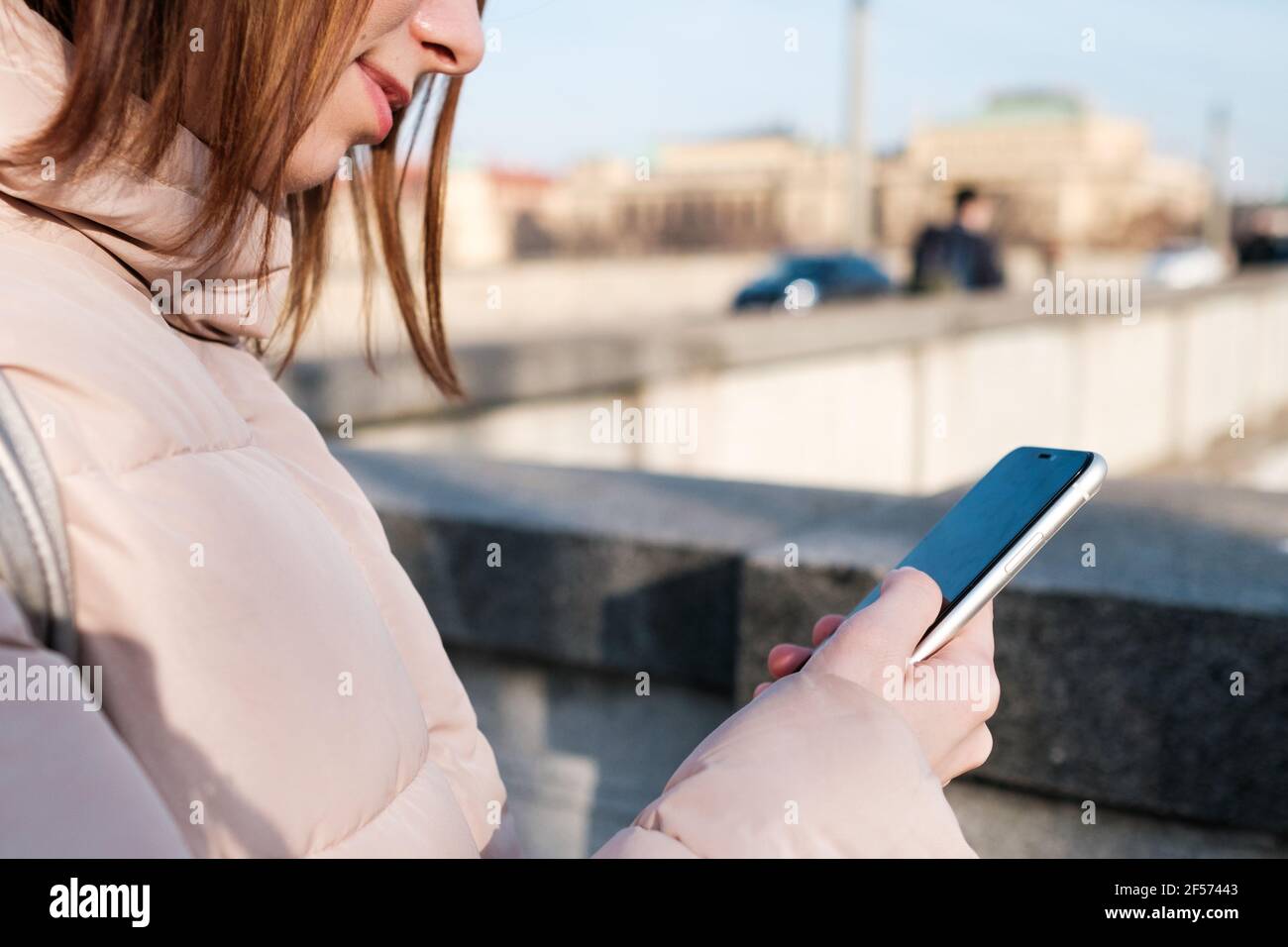 Primo piano le mani della donna che tengono uno smartphone. La bambina usa la messaggeria, la connessione wi-fi gratuita o la connessione internet all'esterno della strada. Foto Stock