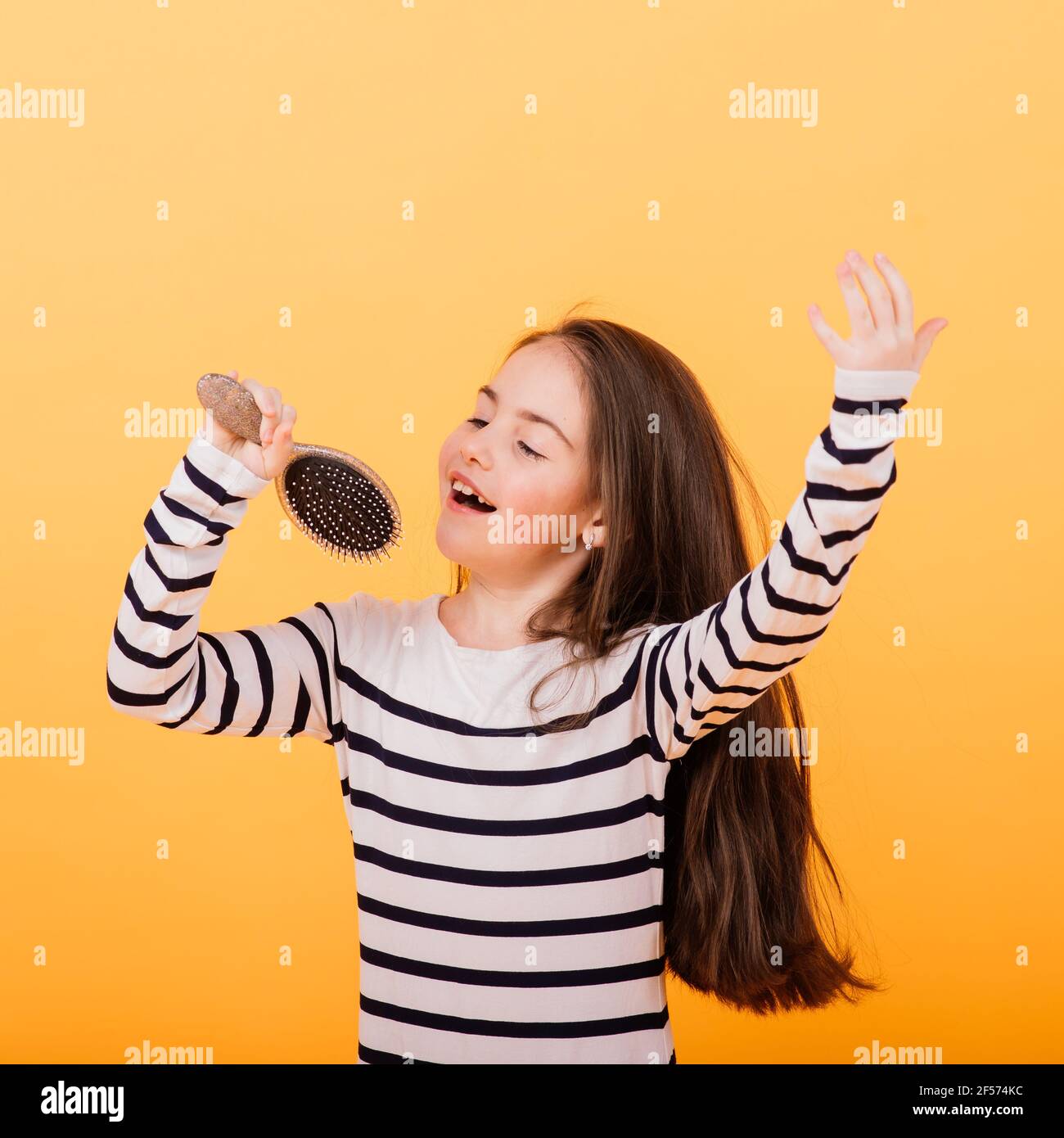 Bambina che canta usando la spazzola per capelli come microfono Foto stock  - Alamy
