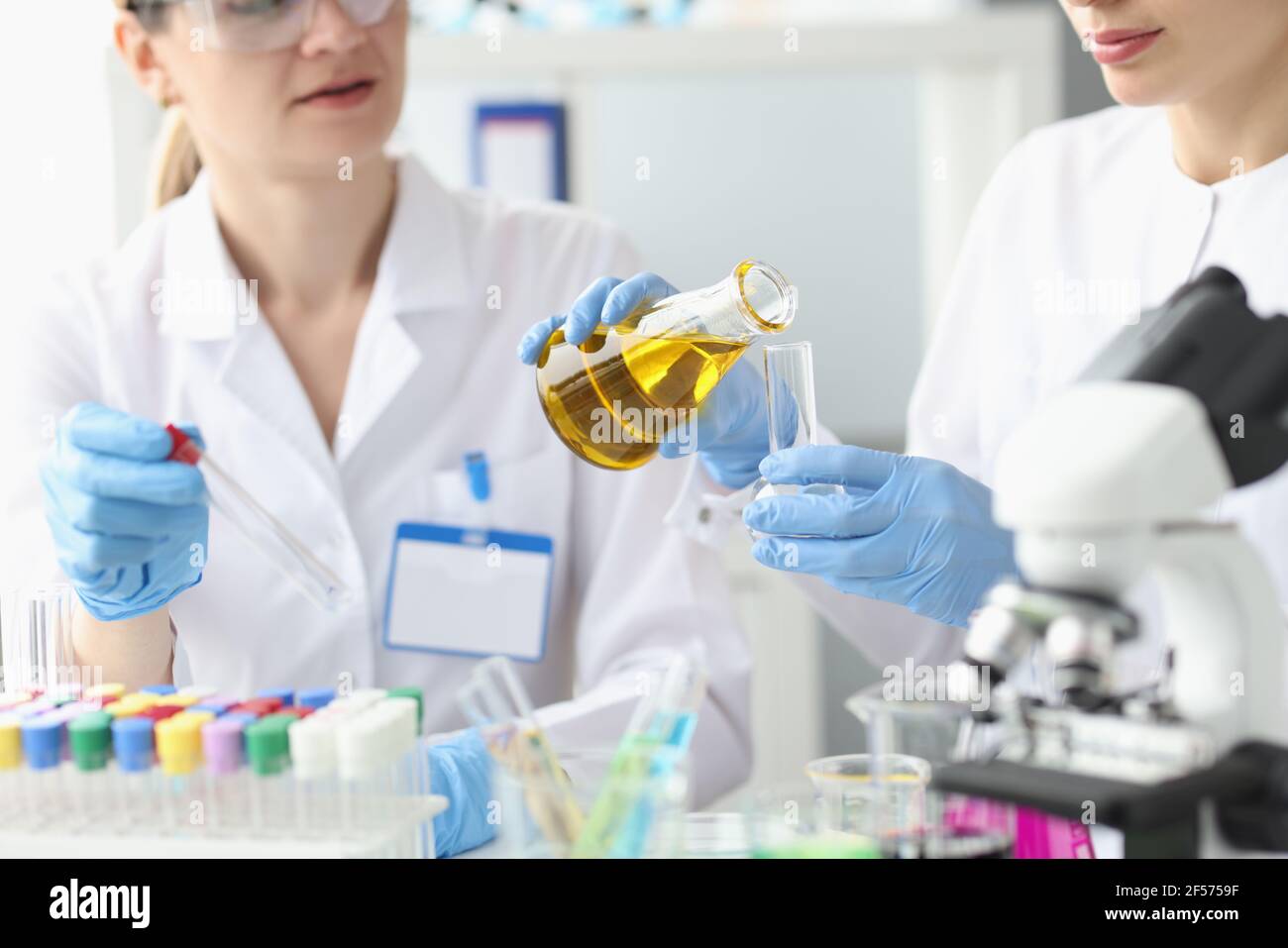 Due ricercatori in laboratorio esaminano il liquido dorato nella provetta Foto Stock