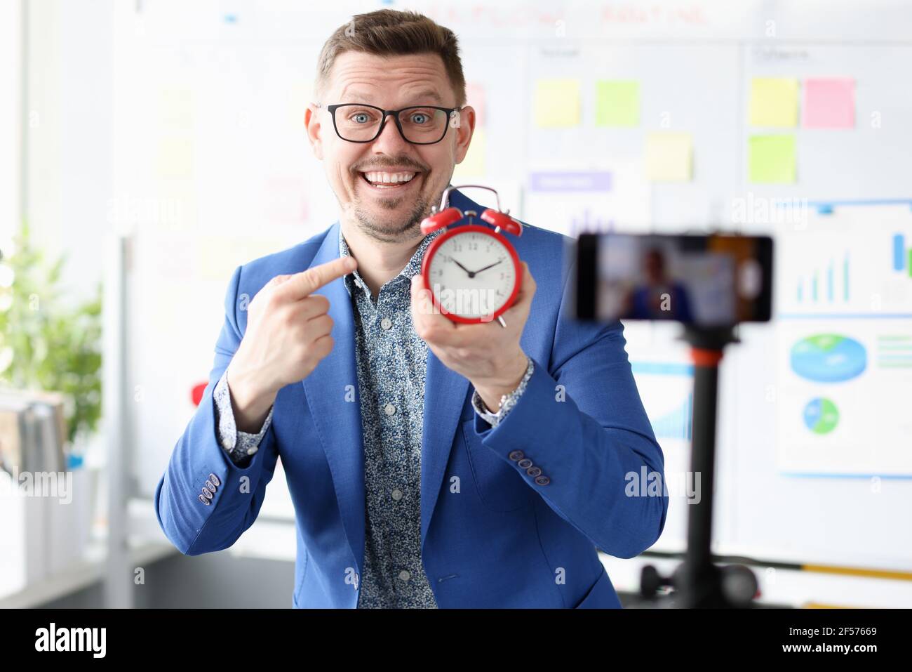 Ritratto di un uomo d'affari sorridente che tiene in mano la sveglia rossa mano Foto Stock