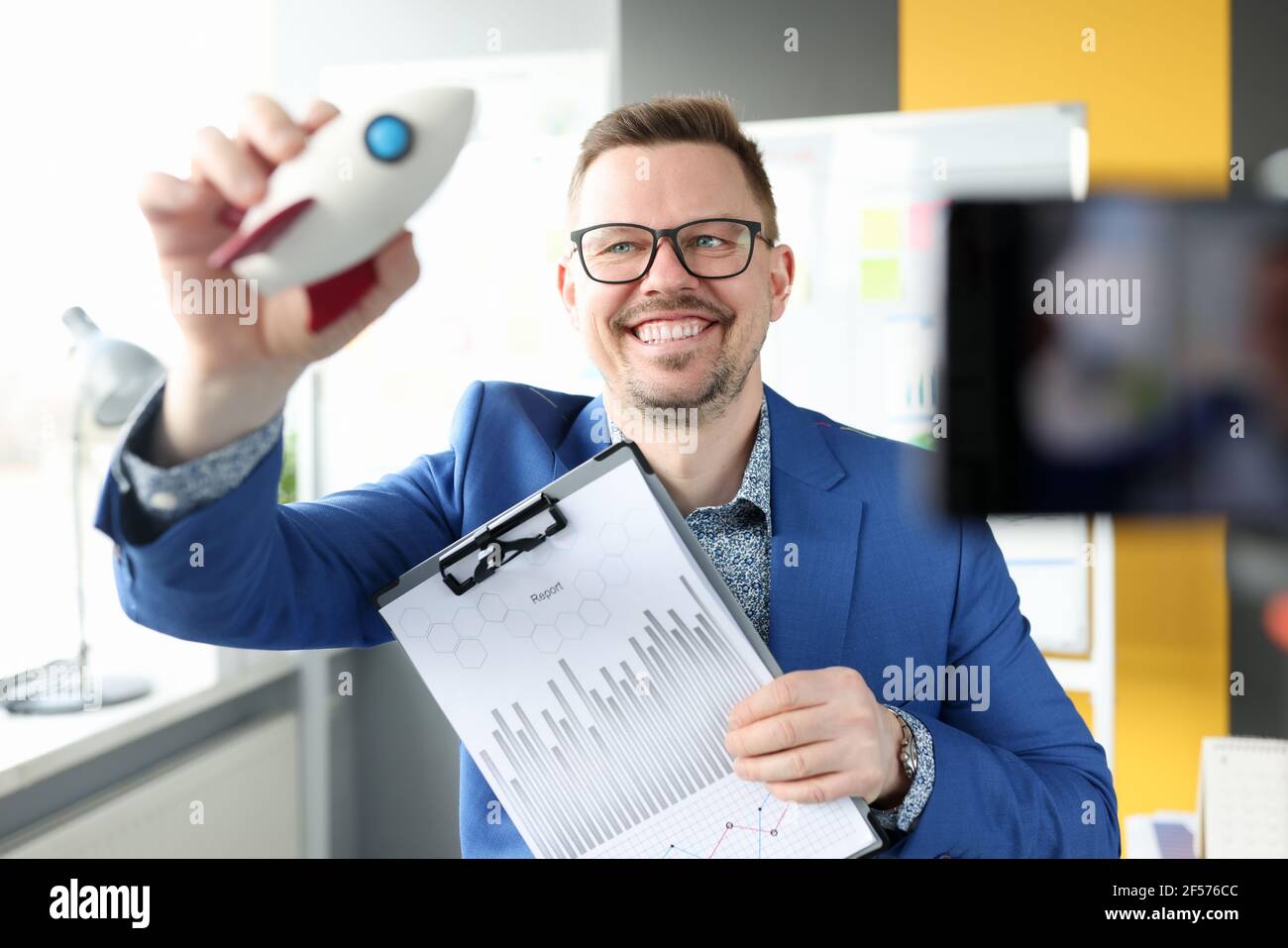 Uomo sorridente che tiene in mano il razzo e le carte aziendali Foto Stock