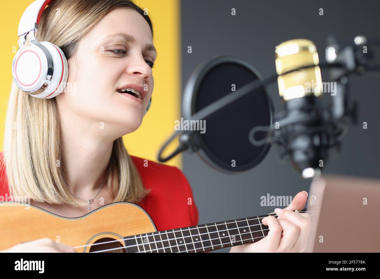 Ritratto della donna che canta nelle cuffie davanti al microfono Foto Stock