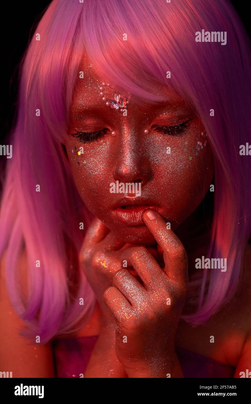 Una ragazza con capelli viola e pelle incandescente. Un alieno o una fata con pelle incandescente. Occhi chiusi. Cute viso bambola. Foto Stock
