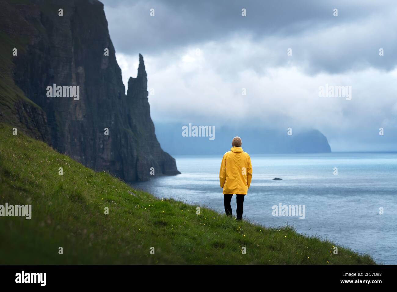 Tourist con zaino in giacca gialla guarda Witches Finger scogliere Foto Stock