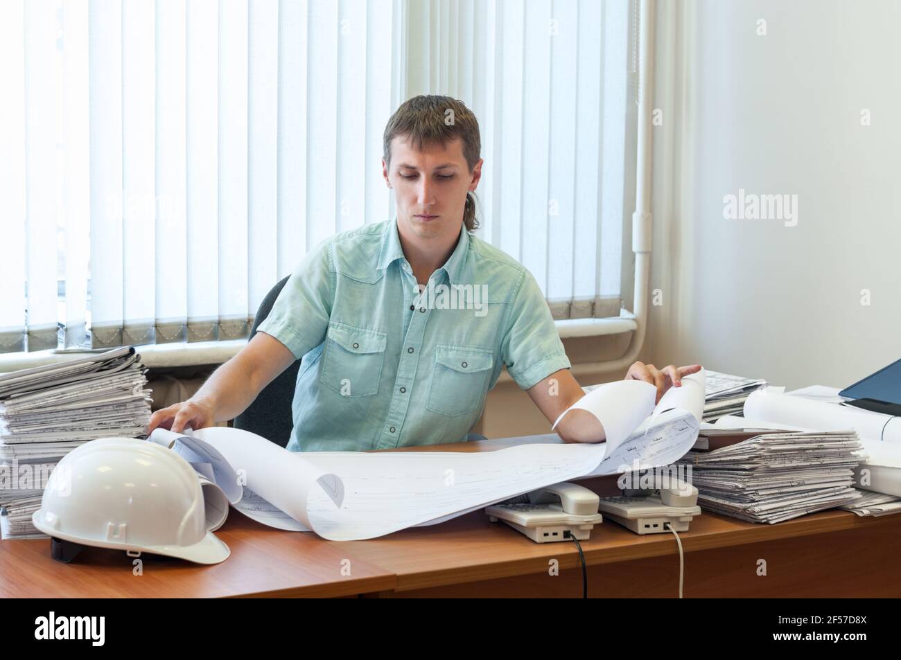 Ingegnere uomo qualificato in progettazione strutturale lavorando sul dettagliato report di progetto in un ufficio Foto Stock