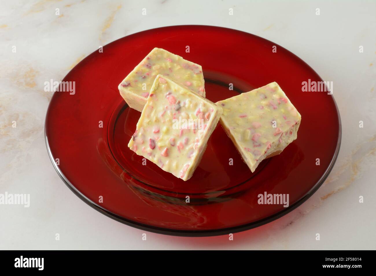 Fragola rabarbaro bianco cioccolato pezzi da bar pezzi su vetro rosso piatto da dessert Foto Stock