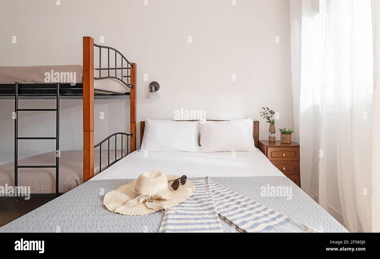 Vista frontale della camera da letto interna in stile semplice con letto matrimoniale classico e letto a castello con scale in metallo, mobili in legno, su copia bianca vuota della parete Foto Stock