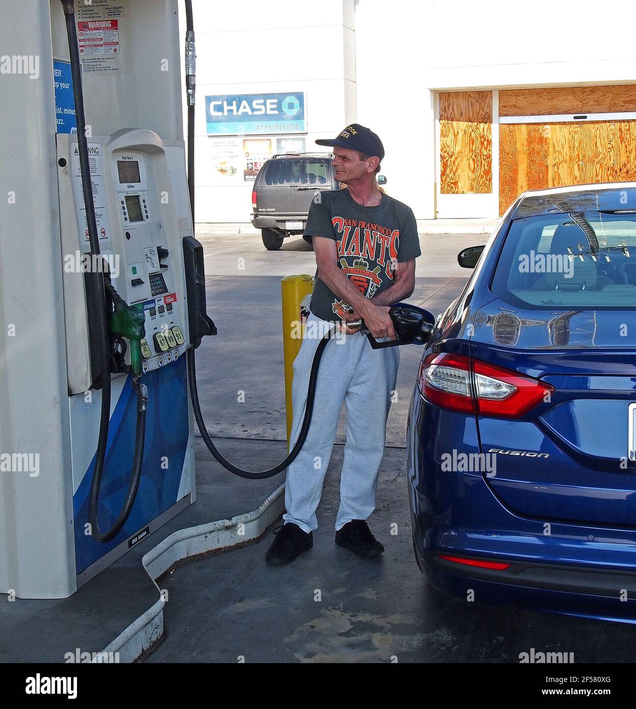 L'uomo anziano pompa il gas nell'automobile ibrida di Ford in California Foto Stock