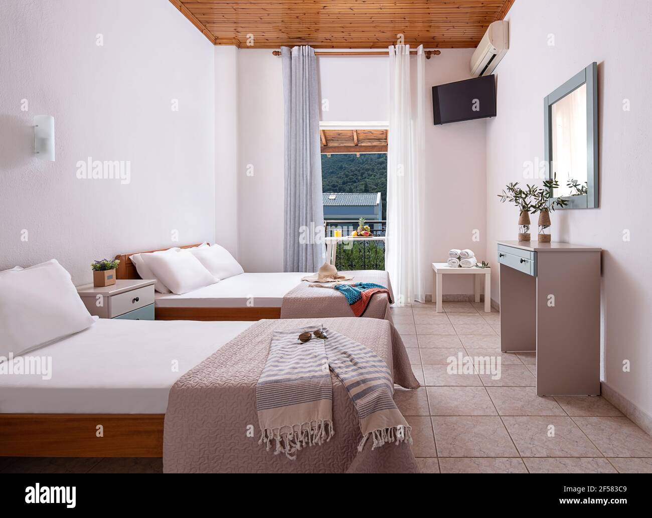 Interno bianco della camera da letto dell'appartamento con letto singolo, matrimoniale king size. Camera per famiglie con soffitto in legno, pavimento piastrellato, porta aperta, vie di campagna Foto Stock