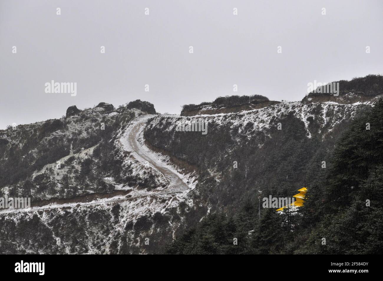 Tempio nepalese con tetto giallo sulla cima della collina, strada a spirale coperta di neve, strada che conduce al tempio Foto Stock