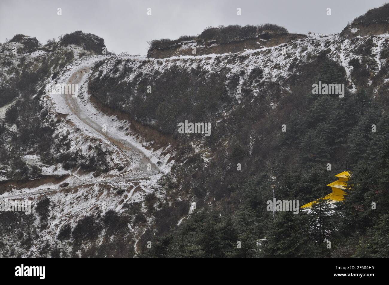 Tempio nepalese con tetto giallo sulla cima della collina, strada a spirale coperta di neve, strada che conduce al tempio Foto Stock