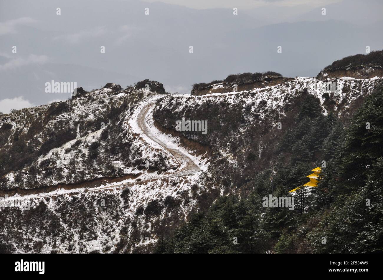 Tempio nepalese con tetto giallo sulla cima della collina, strada a spirale coperta di neve, strada che conduce al tempio Foto Stock
