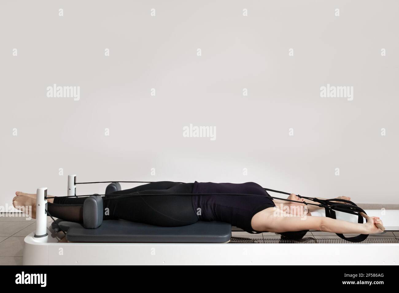 Una donna che fa esercizi pilates su un letto riformato. Foto Stock